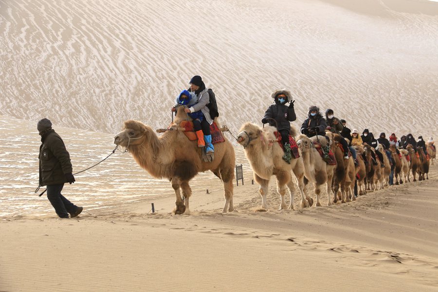 游客在甘肅省敦煌市鳴沙山月牙泉景區游覽。張曉亮攝