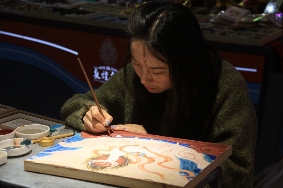 泥板畫藝人在敦煌夜市繪制泥板畫作品。張曉亮攝