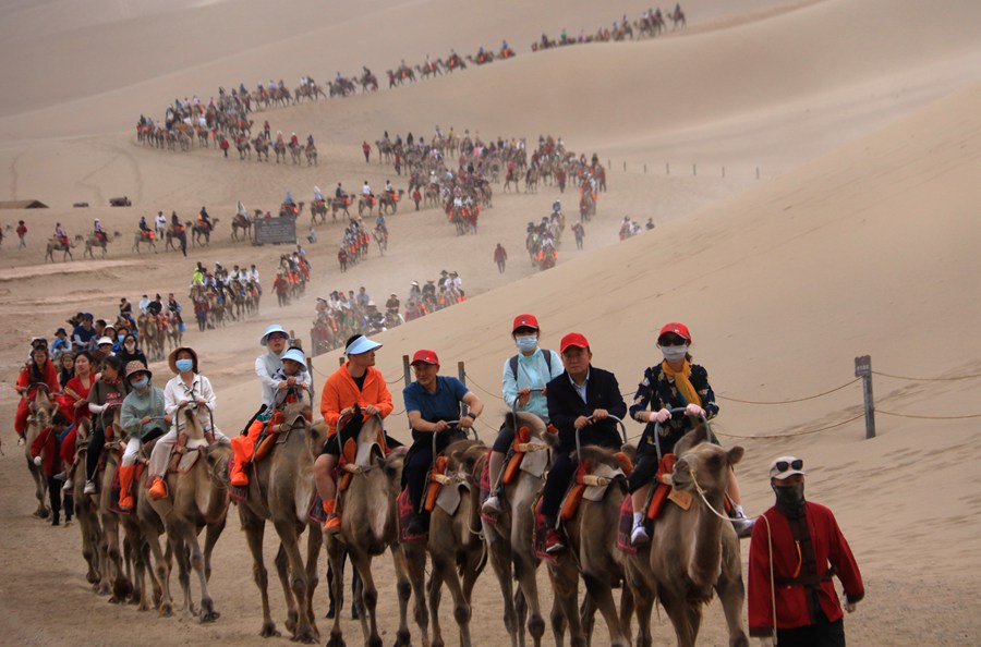 端午假期，游客在甘肅省敦煌市鳴沙山月牙泉景區游覽。張曉亮攝