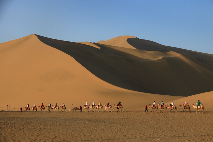 端午假期，游客在甘肅省敦煌市鳴沙山月牙泉景區游覽。張曉亮攝