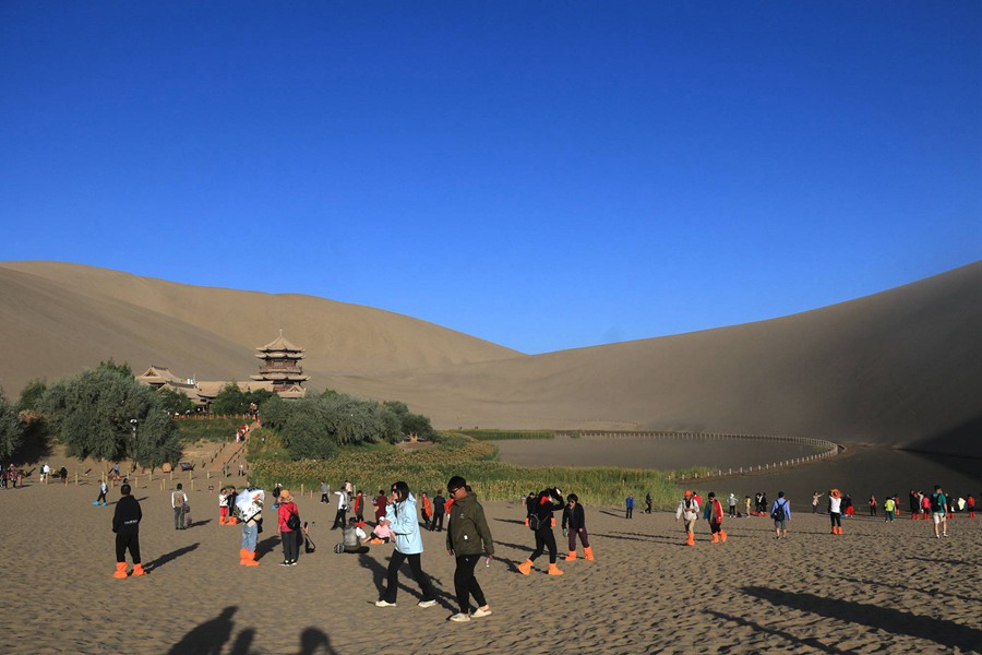 游客在甘肅省敦煌市鳴沙山月牙泉景區游覽。張曉亮攝