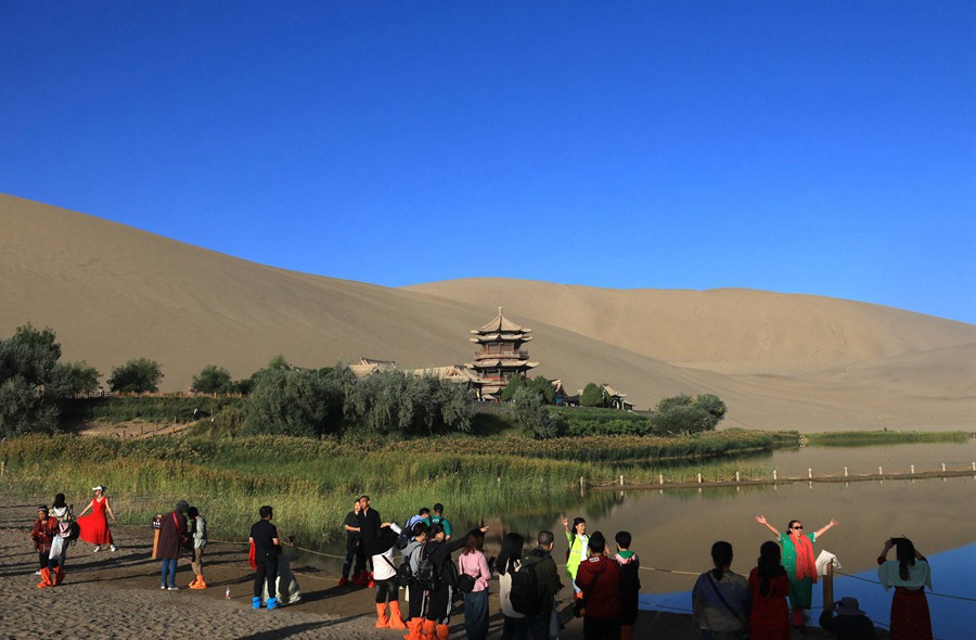 游客在甘肅省敦煌市鳴沙山月牙泉景區游覽。張曉亮攝