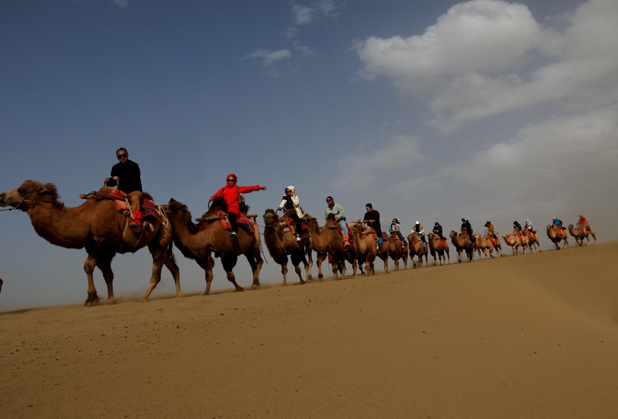 游客在甘肅省敦煌市鳴沙山月牙泉景區游覽。張曉亮攝