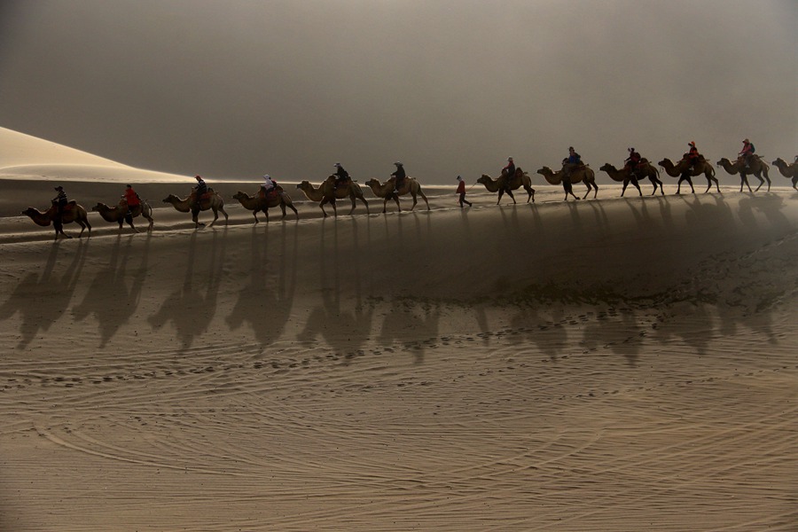 游客在甘肅省敦煌市鳴沙山月牙泉景區游覽。張曉亮攝