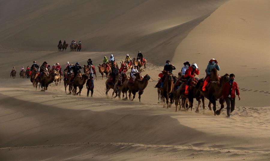 游客在甘肅省敦煌市鳴沙山月牙泉景區游覽。張曉亮攝