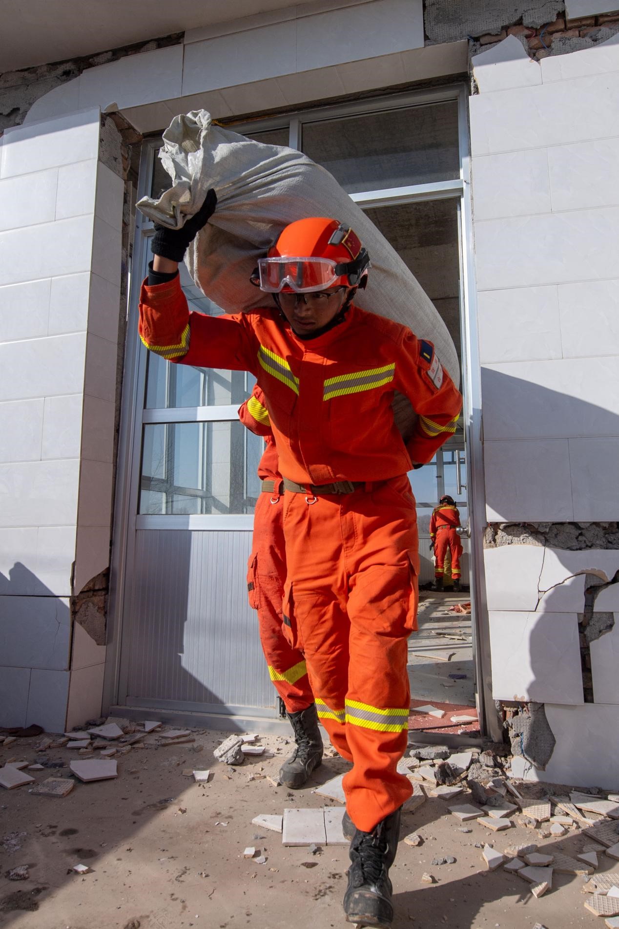 12月21日，在積石山縣石塬鎮石塬村，消防救援人員正在幫助群眾轉運物資。人民網記者 翁奇羽攝