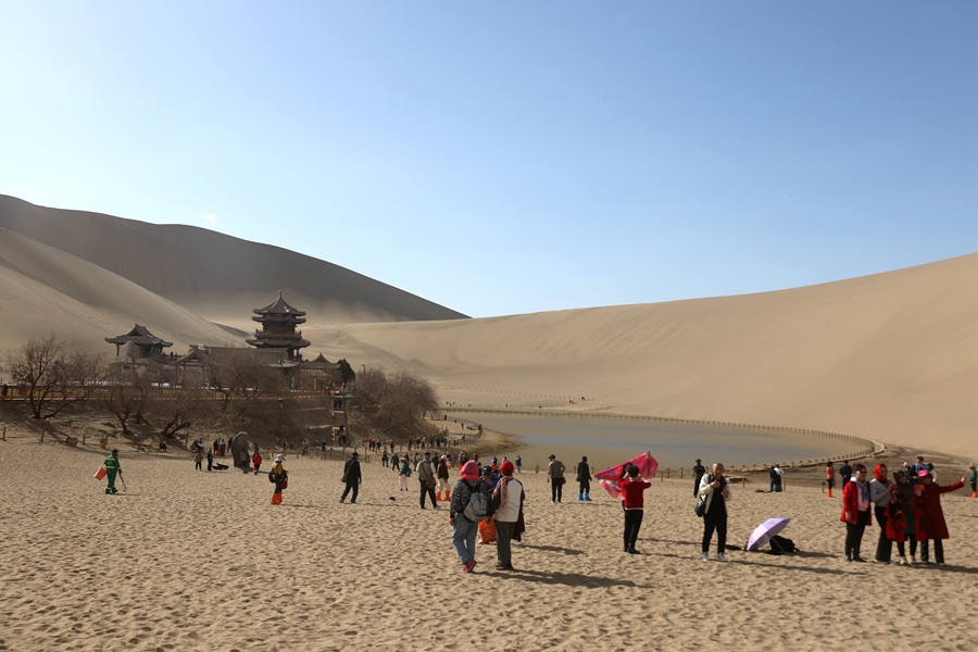 3月24日，游客在甘肅省敦煌市鳴沙山月牙泉景區游覽。張曉亮攝