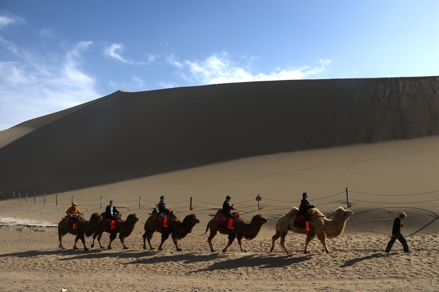 3月24日，游客在甘肅省敦煌市鳴沙山月牙泉景區游覽。張曉亮攝