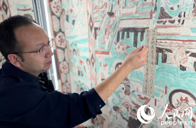 敦煌研究院文物保護技術服務中心副主任水碧紋向人民網“行進中國”甘肅調研采訪團介紹壁畫修復技術。人民網記者 徐冬兒攝