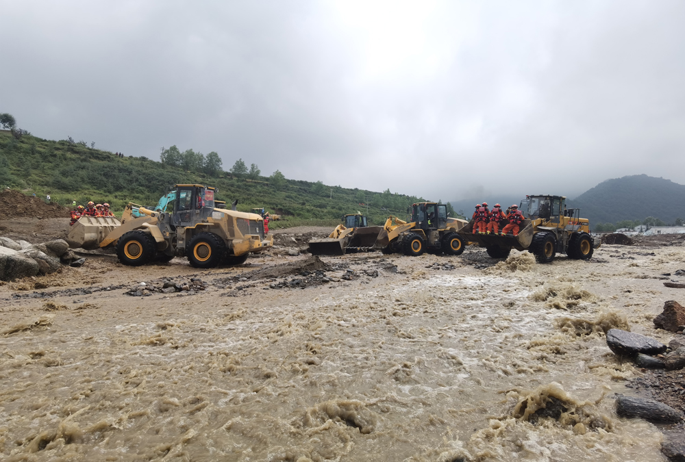 8月9日，甘肅省森林消防總隊在馬坡鄉舊莊溝村沿河道繼續搜尋被困人員，消防員乘載裝載機挺近抗洪搶險一線。張小軍 攝