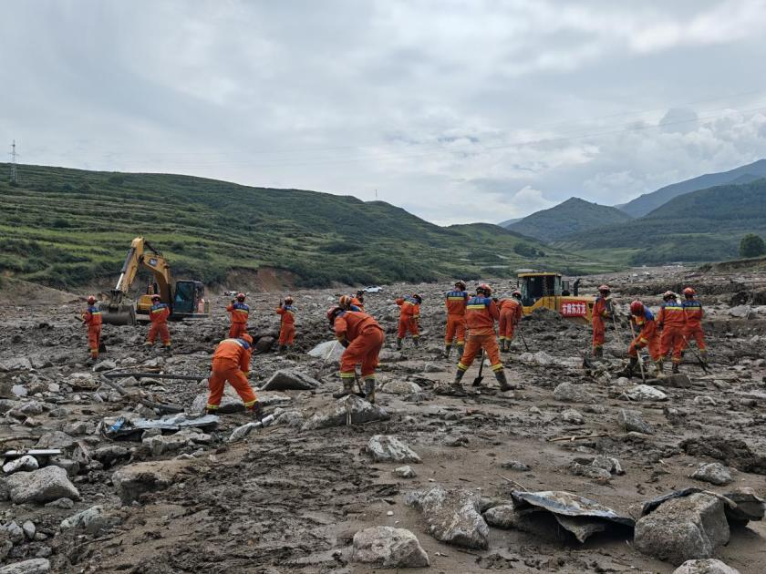8月10日15時，消防救援人員在災情嚴重的馬坡鄉馬蓮灘村河溝區域，聯合重型機械圍繞一處塌陷建筑展開搜救。甘肅消防供圖