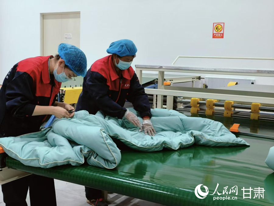 工作人員整理剛剛制作好的艾草被。人民網記者 焦隆攝