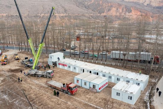 12月22日，在甘肅省臨夏州積石山縣劉集鄉陶家村，施工人員正在吊裝箱式房。人民網記者 翁奇羽攝