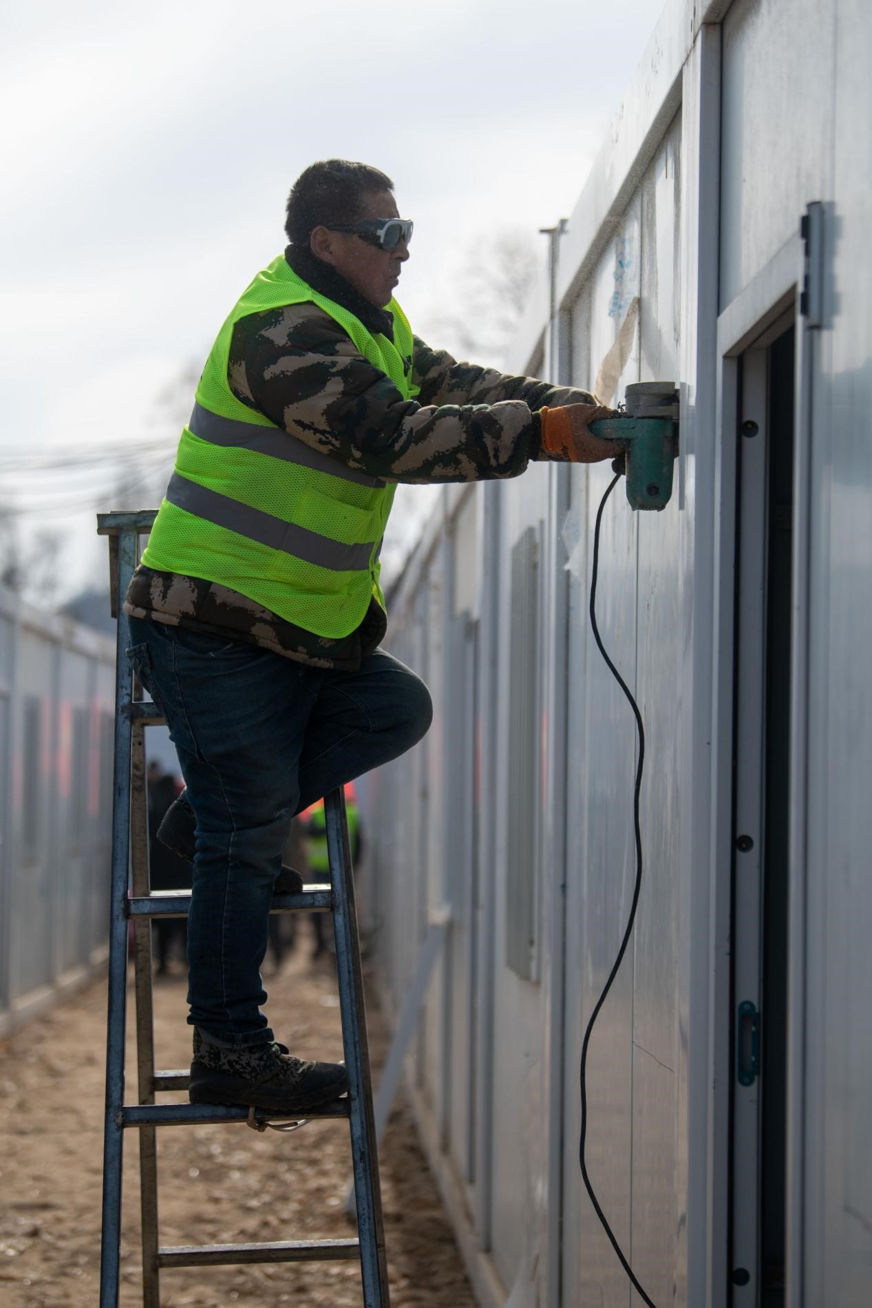 12月22日，在積石山縣劉集鄉陶家村臨時安置箱式房安裝現場，工人正在抓緊施工。人民網記者 翁奇羽攝