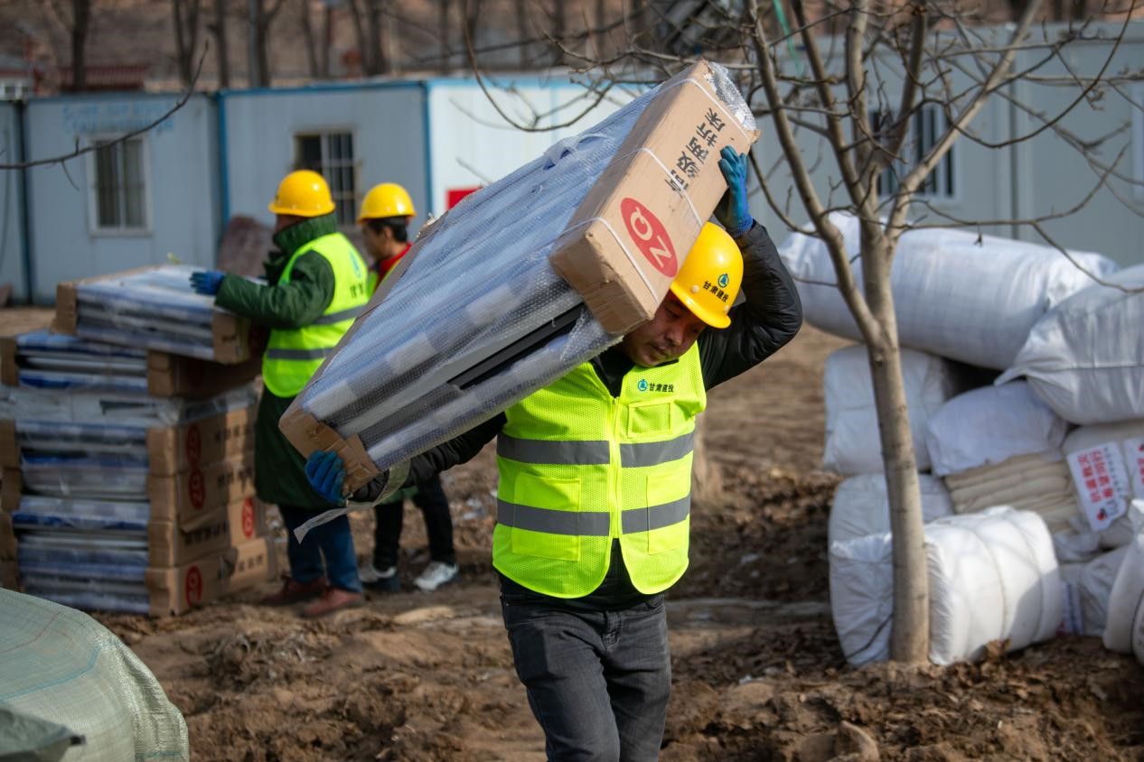 12月22日，在積石山縣劉集鄉陶家村，工人正在往臨時安置箱式房內搬運折疊床。人民網記者 翁奇羽攝