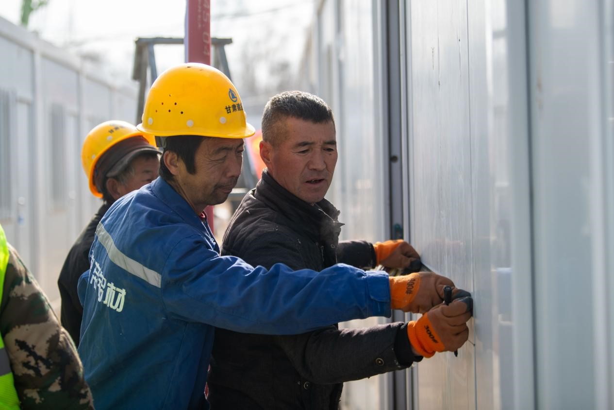 12月22日，在積石山縣劉集鄉陶家村臨時安置箱式房安裝現場，工人正在抓緊施工。人民網記者 翁奇羽攝